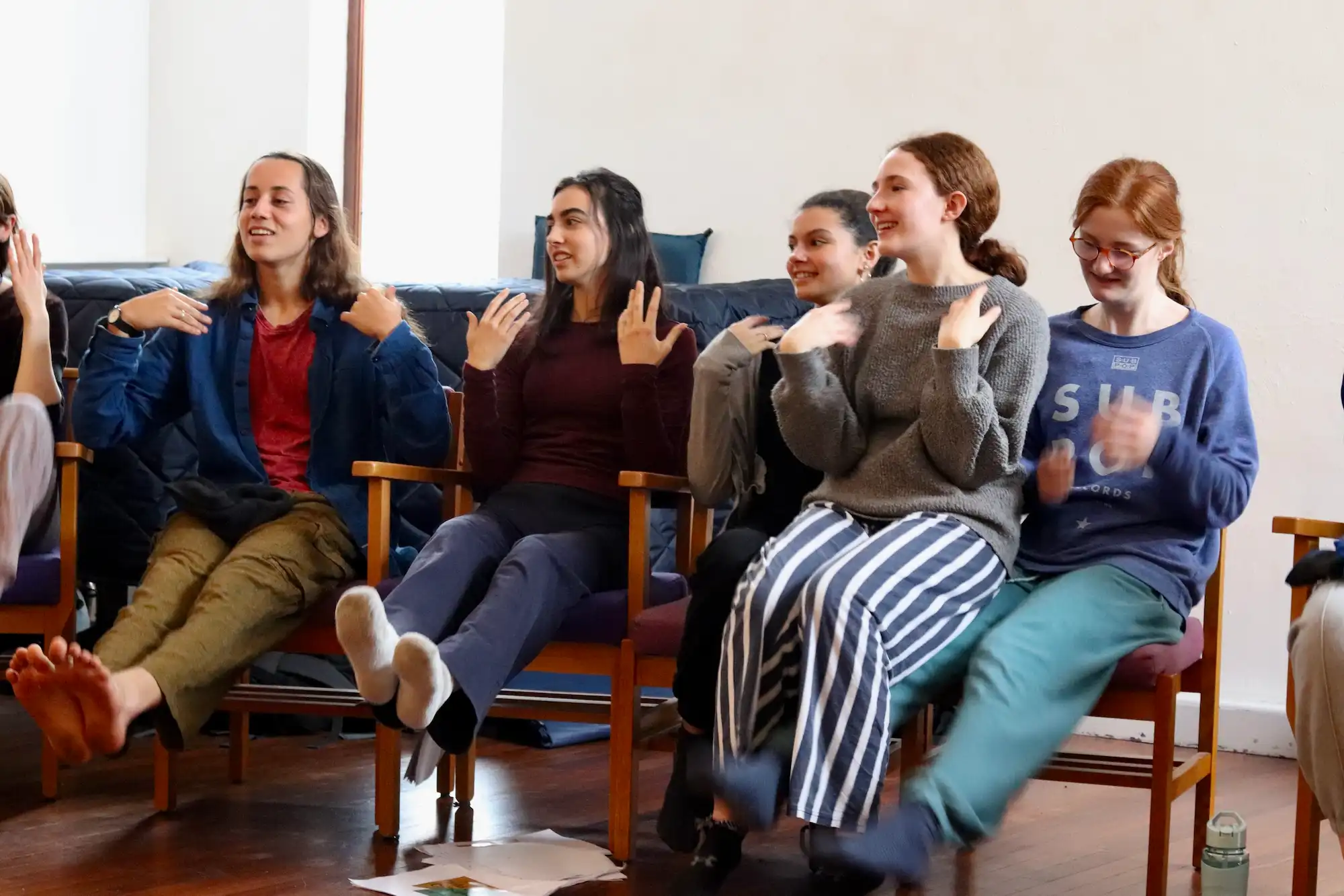 A group of us sitting in a circle with our hands raised a little.